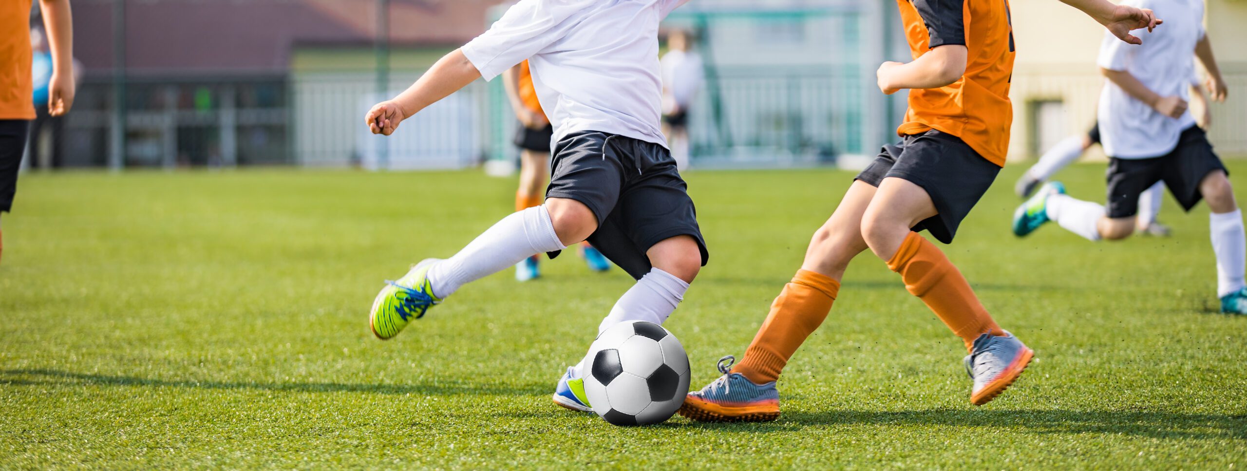Kids Football Players Kicking Ball on Soccer Field. Sports Soccer Horizontal Background. Spectators on Stadium in the Background. Youth Junior Athletes in Red and Blue Soccer Shirts. Sports Education